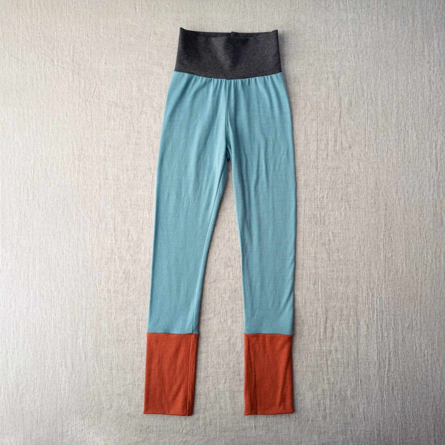 Color-blocked leggings with blue, gray, and red on a textured gray background