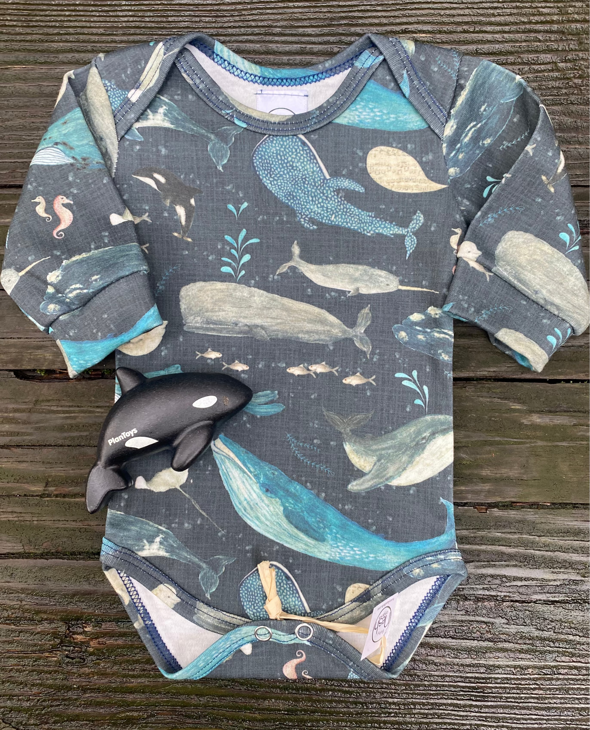 Baby onesie with whale pattern on a wooden surface