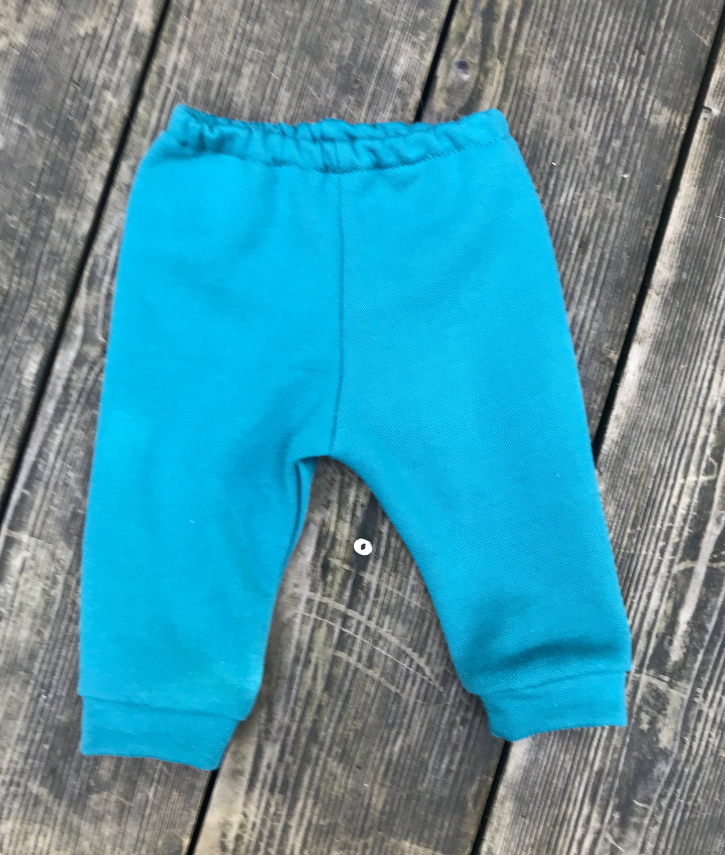 teal baby pants on a wooden surface
