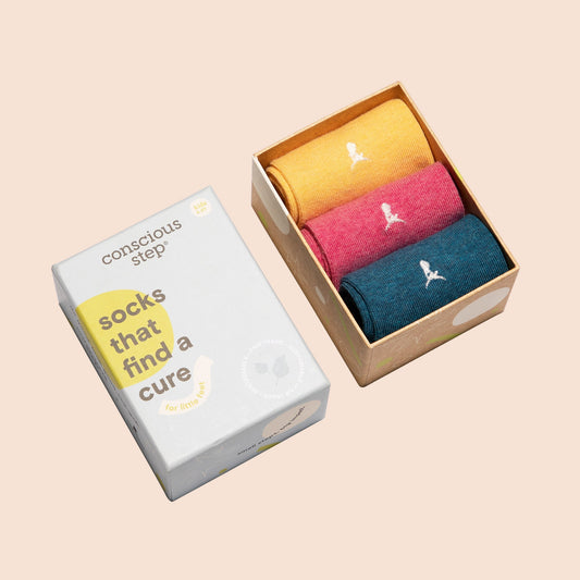 Three pairs of socks in a box with a 'conscious step' packaging on a beige background