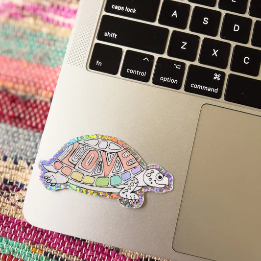 holographic love turtle sticker on a laptop