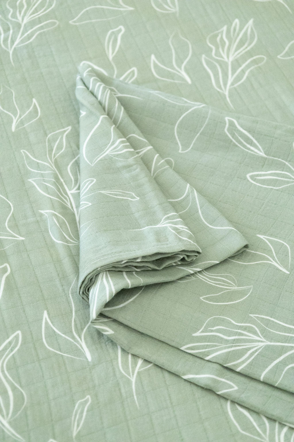 Folded fabric with white leaf pattern on a light green background