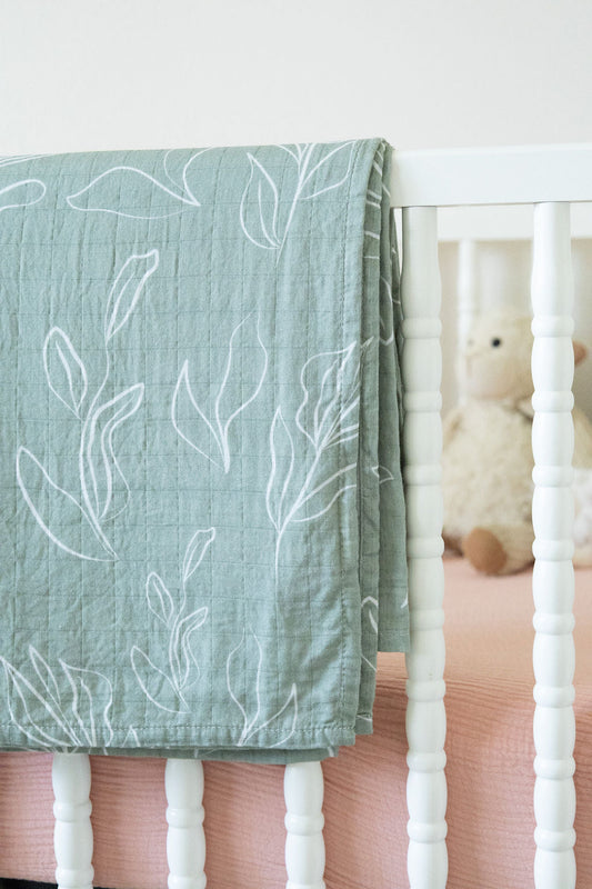 Green crib sheet with leaf pattern on a white crib