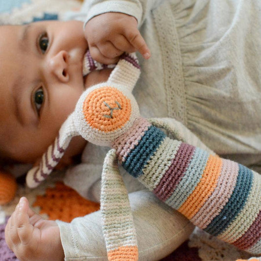 Baby playing with a colorful striped bunny toy