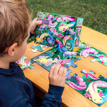 Load image into Gallery viewer, child wearing a blue sweater making Axolotl 20-Piece Puzzle on a wooden table outside
