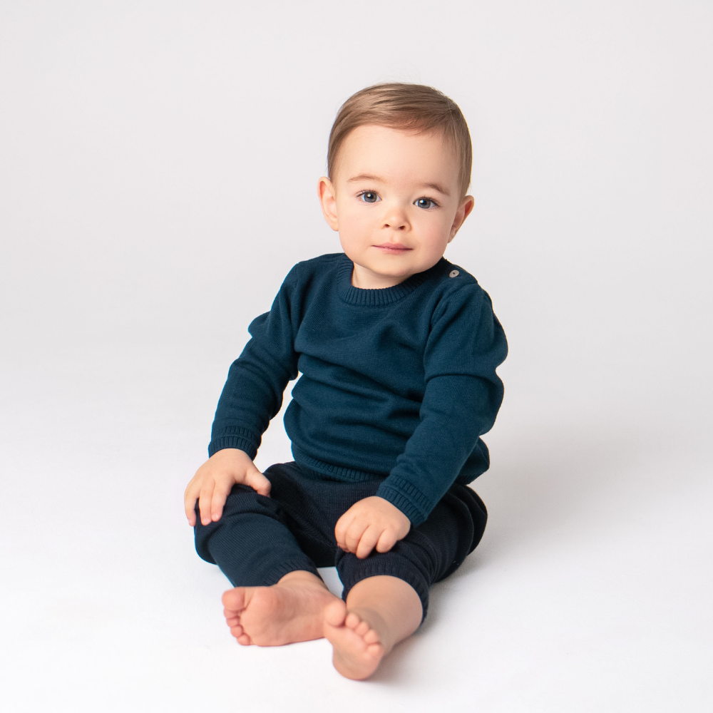 Baby wearing a navy blue sweater and pants on a white background