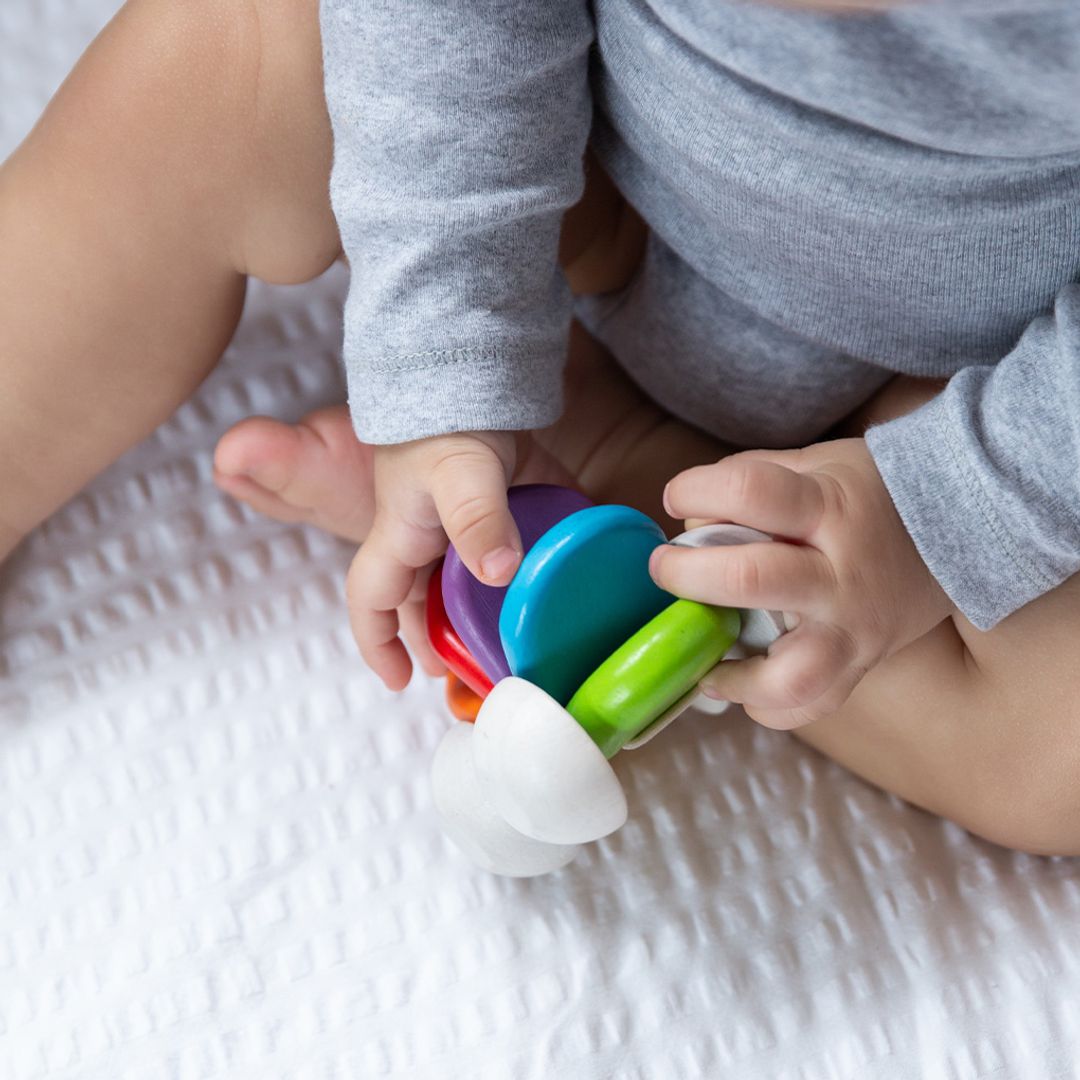Child playing with a colorful toy on a white surface