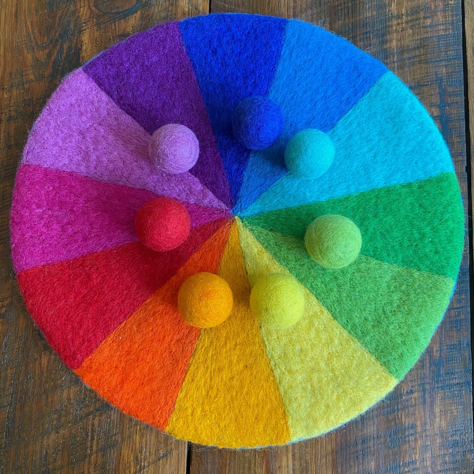 Color wheel with felt balls on a wooden surface