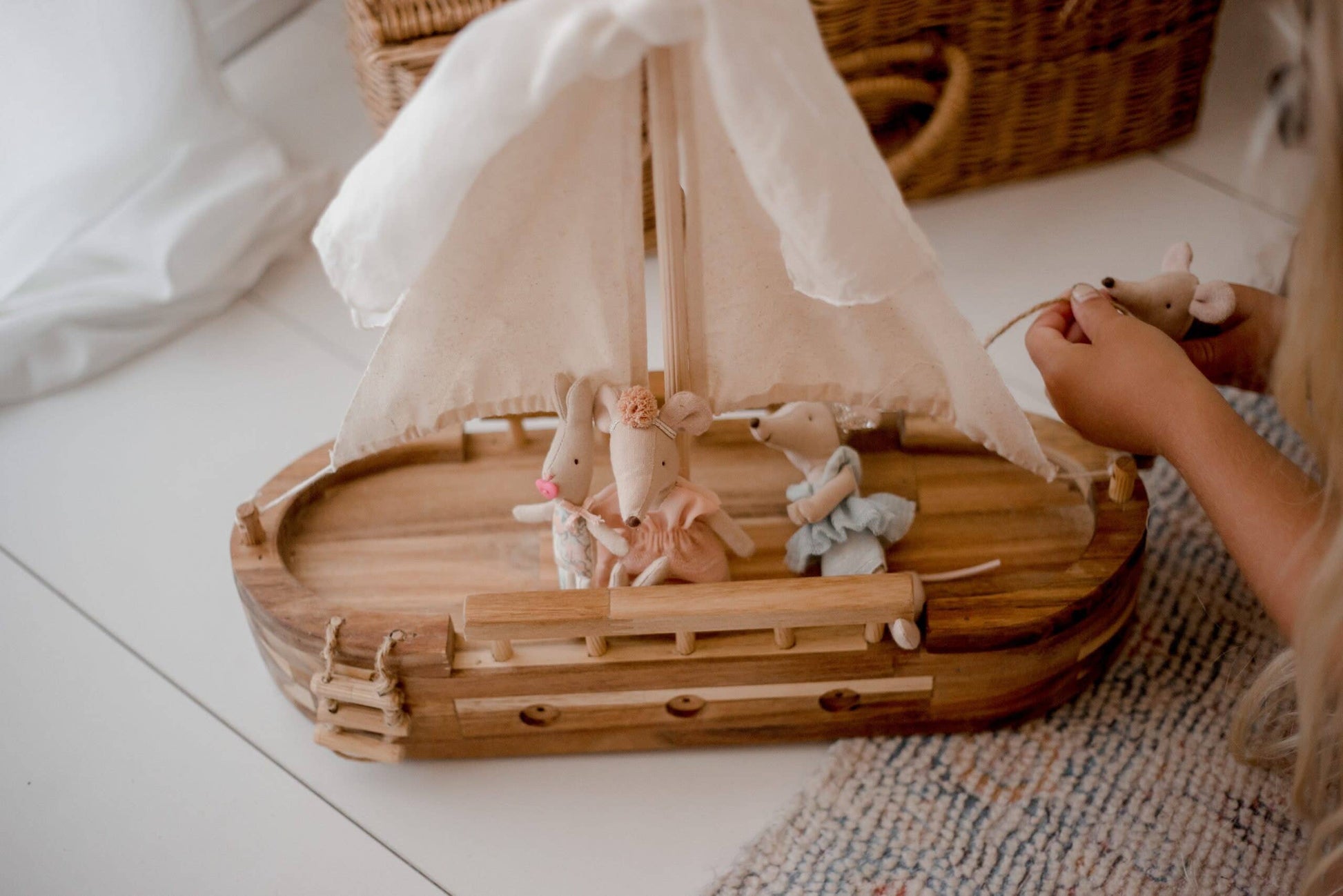 Wooden toy boat with plush mice figures on a light surface