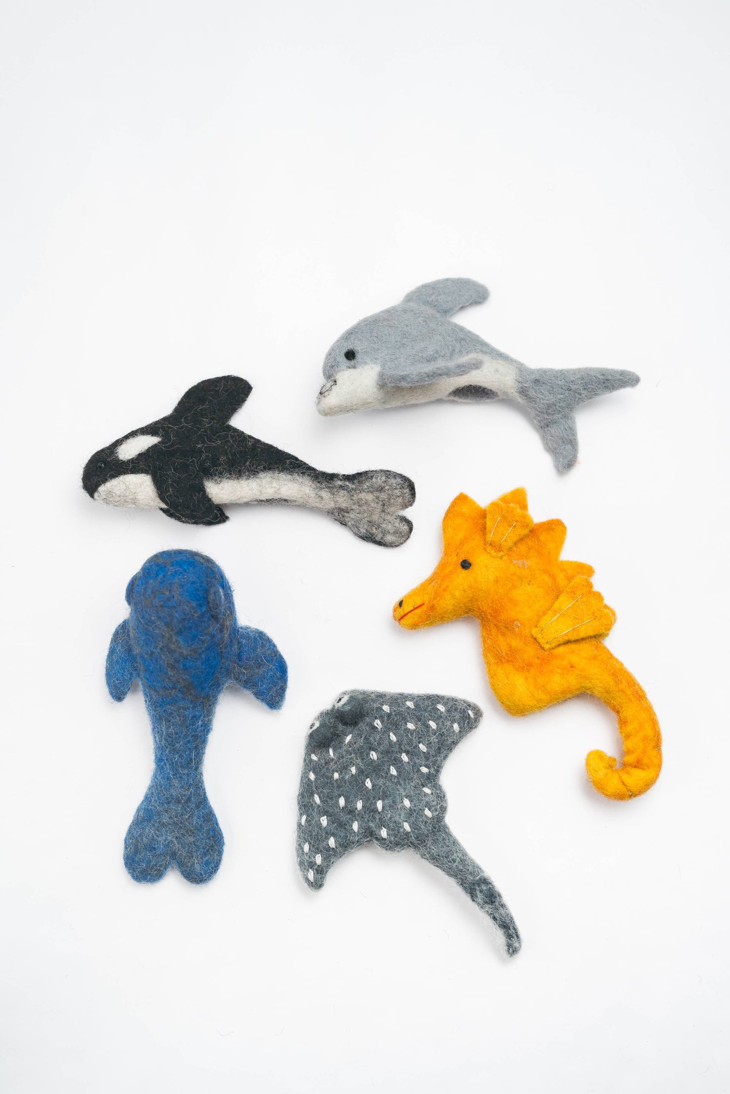 Set of felt animal toys including a dolphin, orca, seahorse, and ray on a white background
