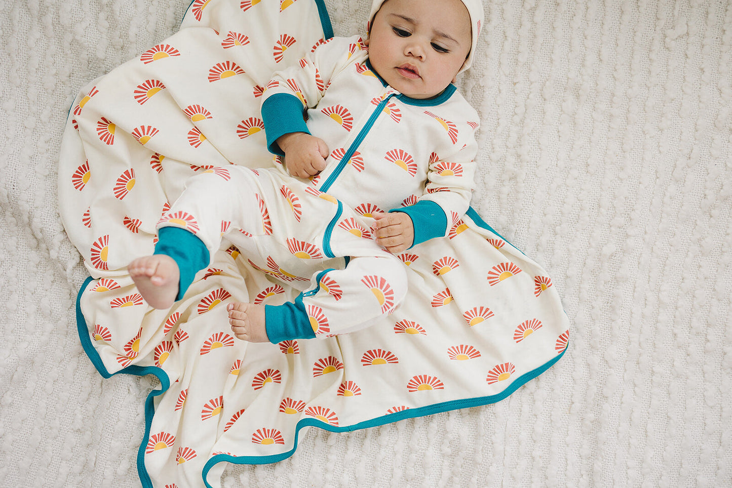 Baby wrapped in a colorful patterned swaddle on a soft surface