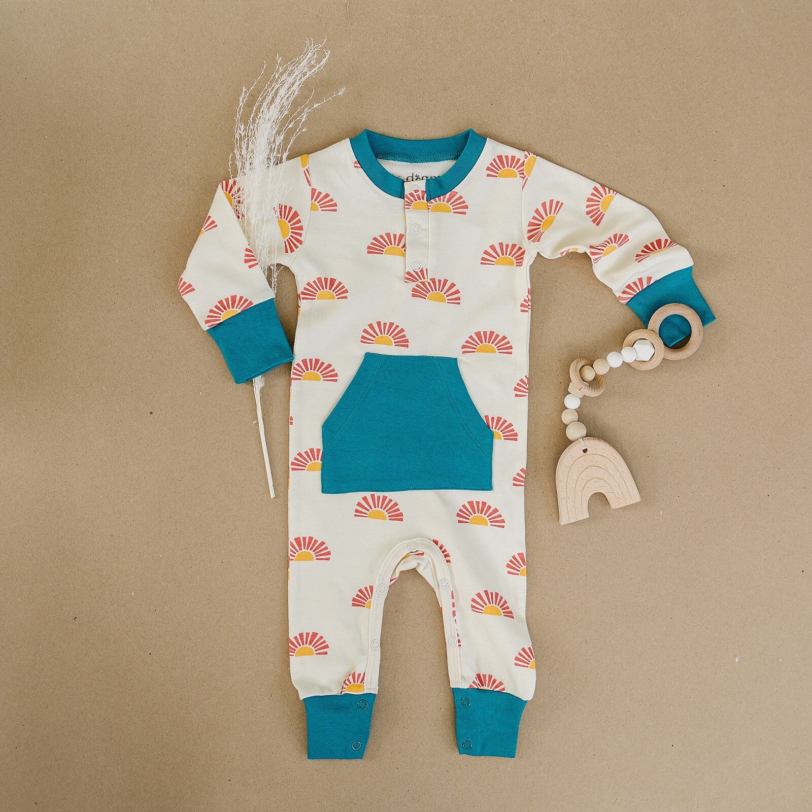 Baby onesie with sun pattern and blue accents on a brown background