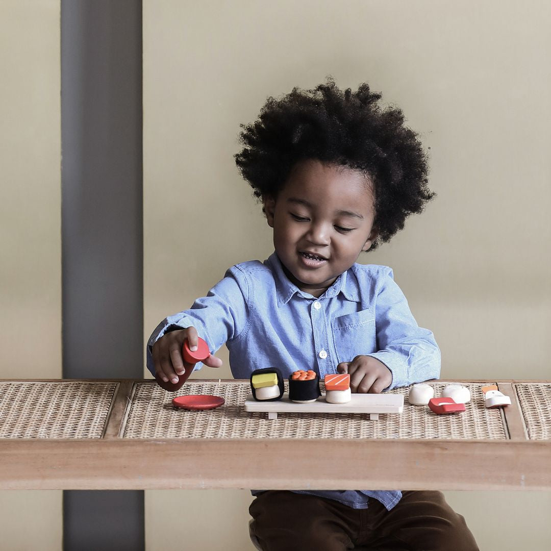 Child playing with toy sushi set on a table