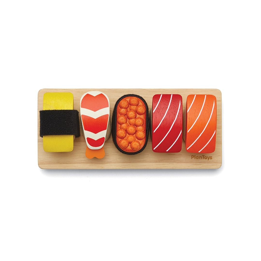 Wooden toy sushi set on a wooden board with PlanToys branding.