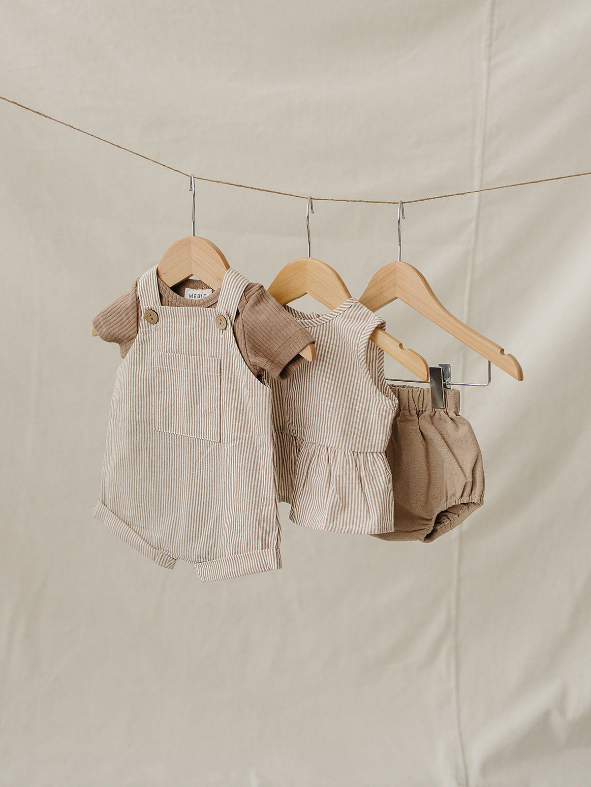 Children's clothing set on hangers against a beige background