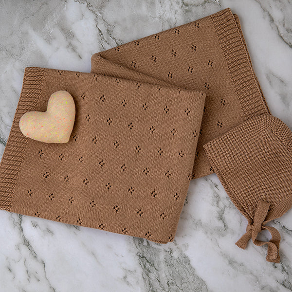 Brown knitted blanket with a heart-shaped object on a marble surface