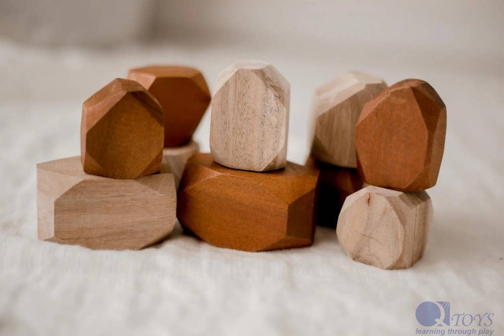 Wooden geometric blocks on a white surface with 'Q Toys' branding.