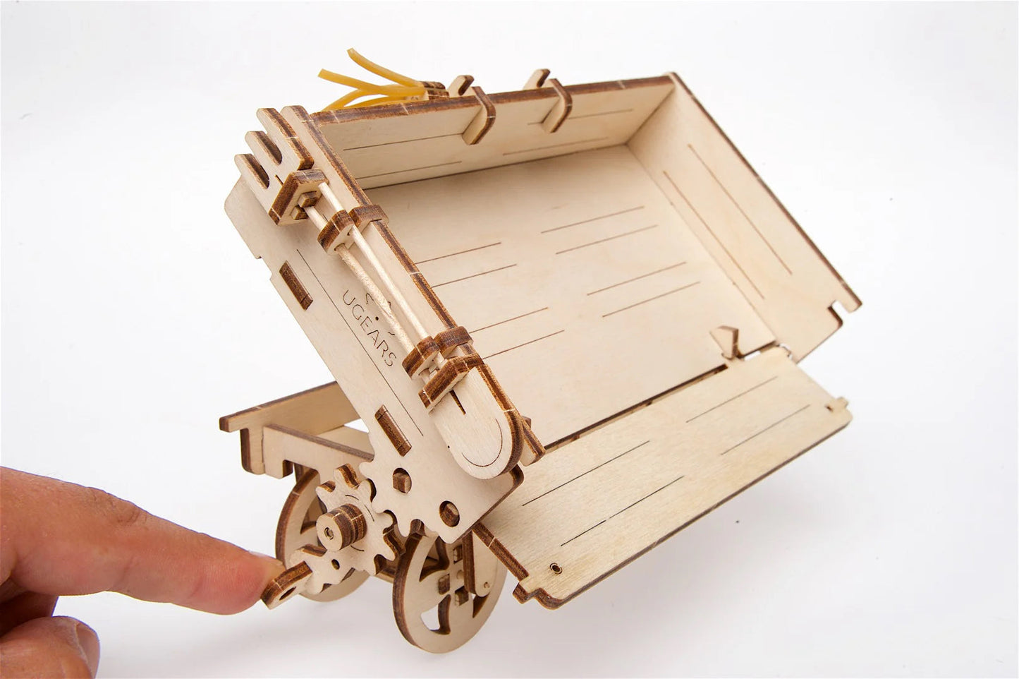 Wooden mechanical model of a trailer with a hand interacting with it on a white background