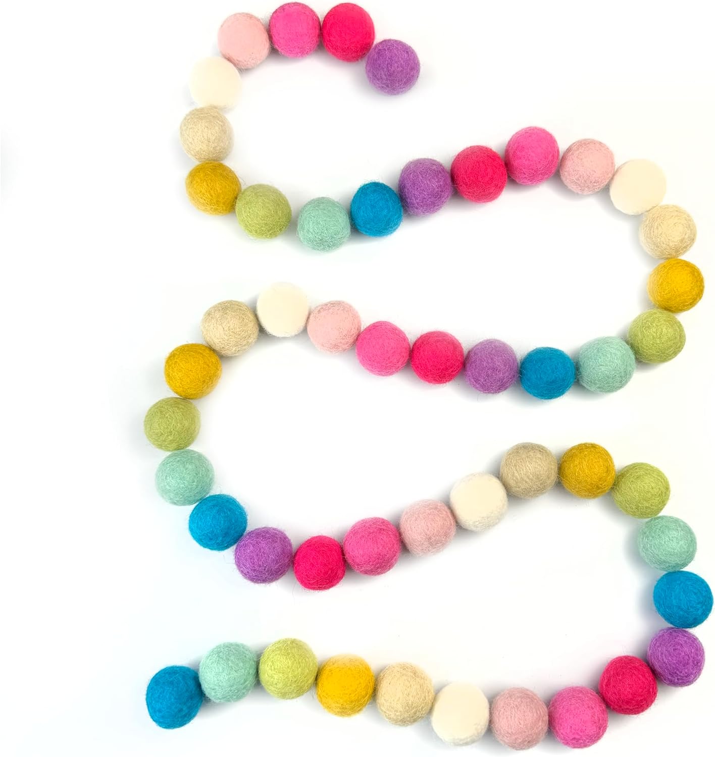 Colorful felt ball garland arranged in a heart shape on a white background
