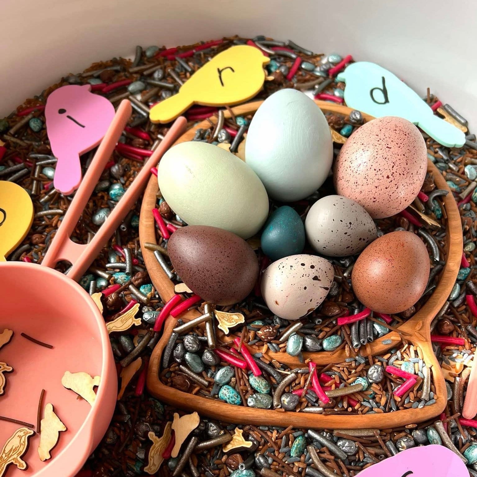 Colorful Easter eggs in a nest with decorative elements on a wooden plate.