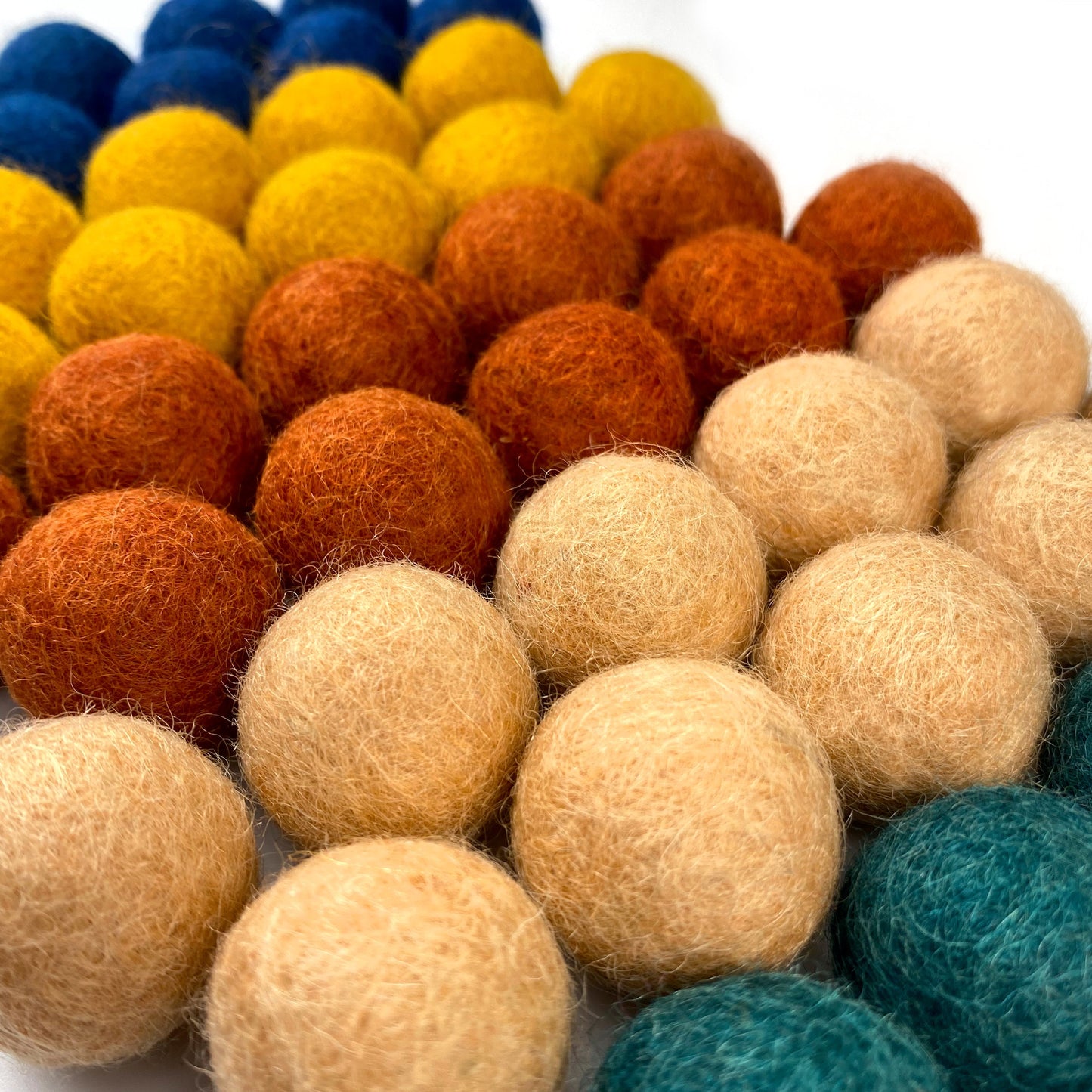 Colorful felt balls arranged in a pattern on a white background