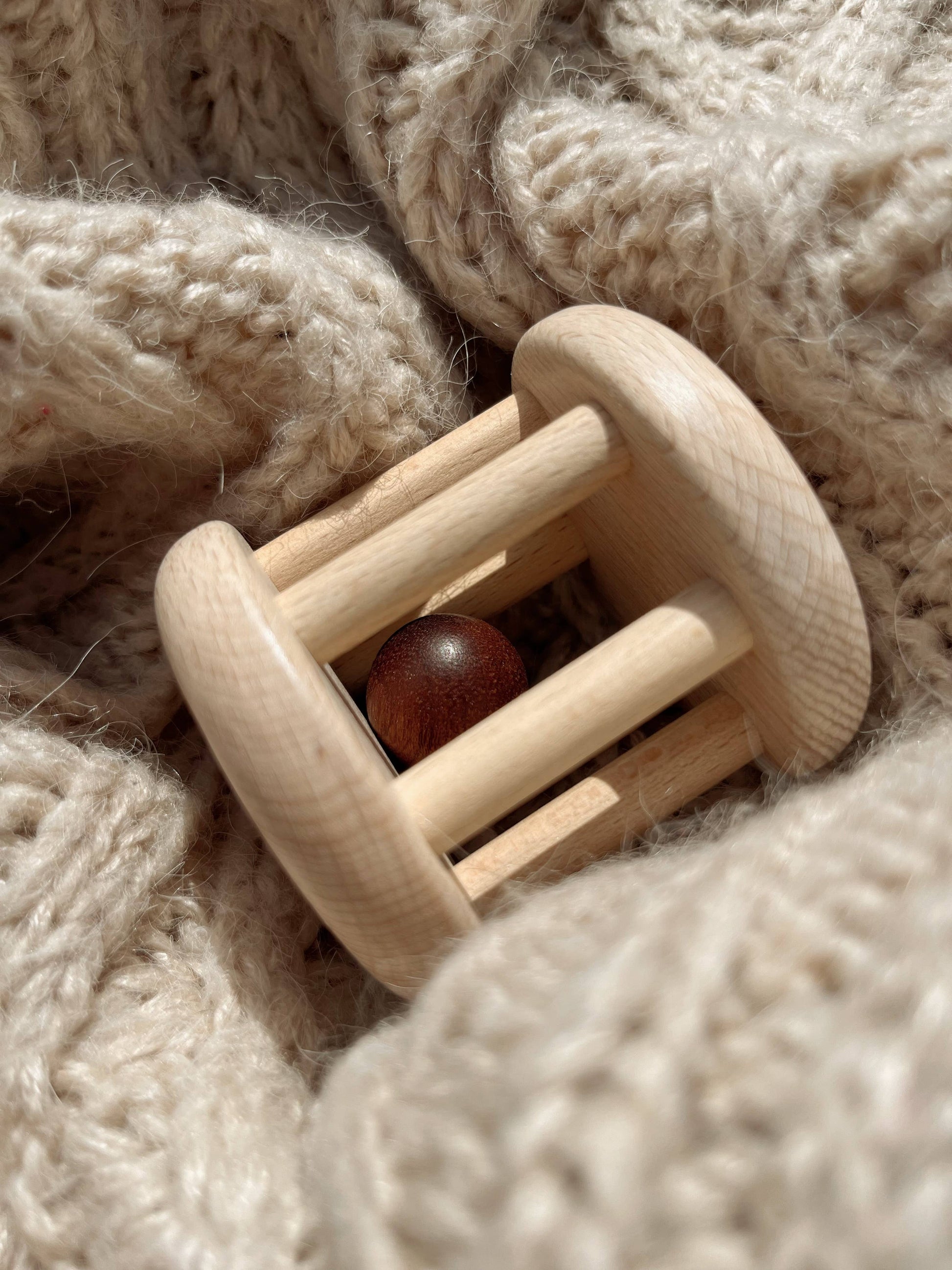 Wooden baby rattle on a soft, textured beige fabric background