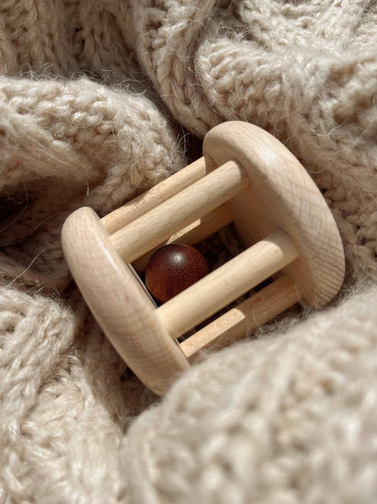 Wooden baby rattle on a soft, textured beige fabric background