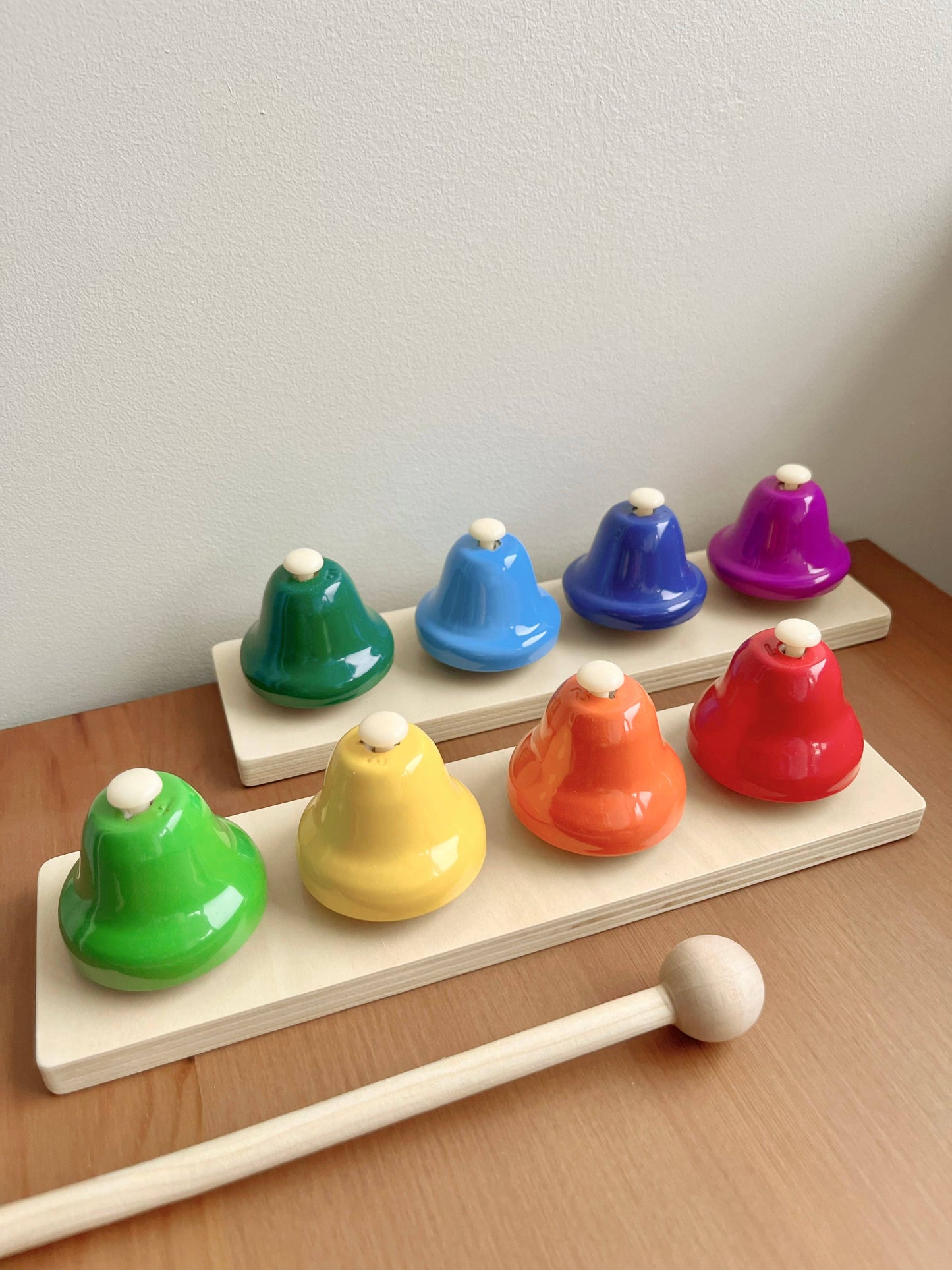 Colorful wooden bell set with a mallet on a wooden surface