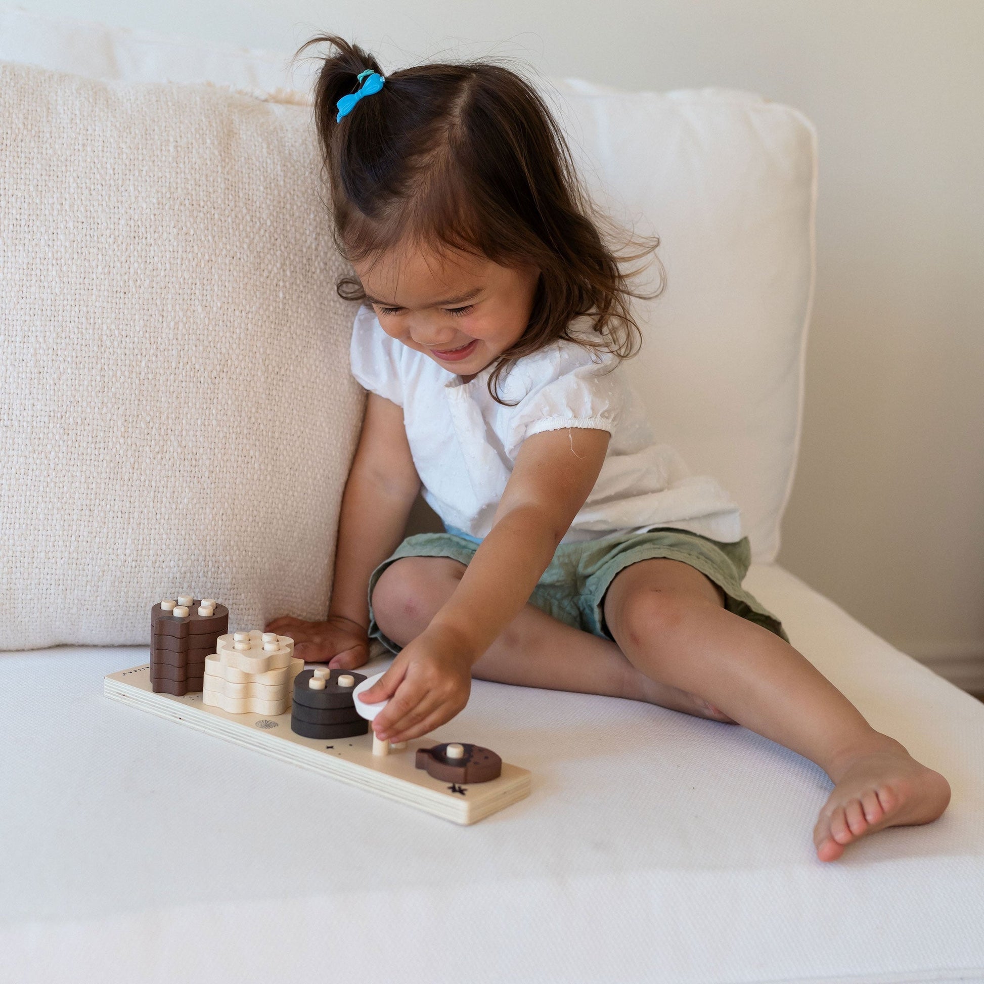 Child playing with wooden toys on a white surface