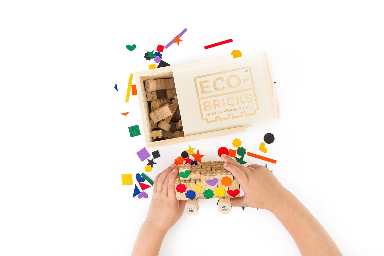 A child's hands playing with Eco-bricks set with colorful felt pieces on a white background
