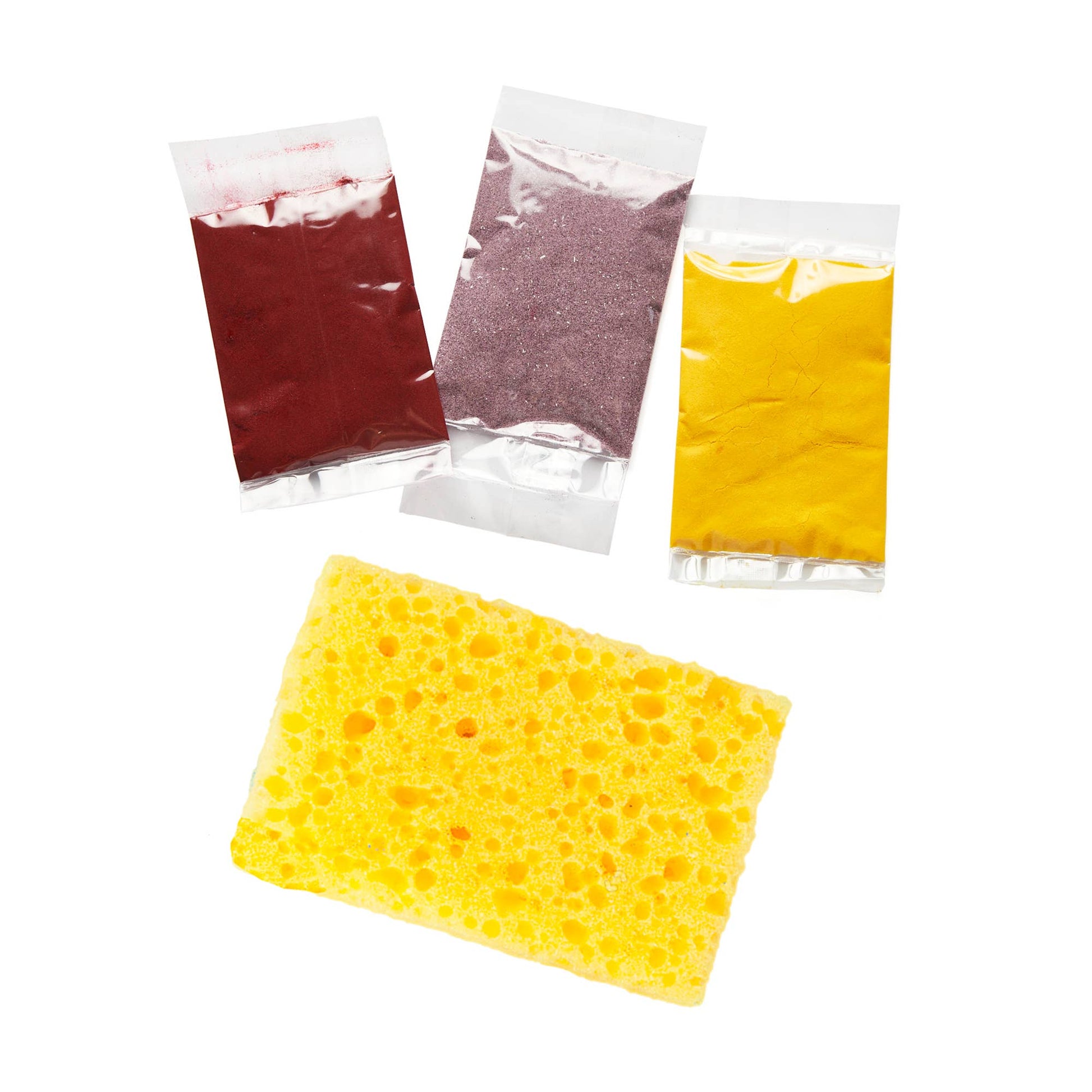 Yellow sponge with three packets of colored dye for paper-making on a white background