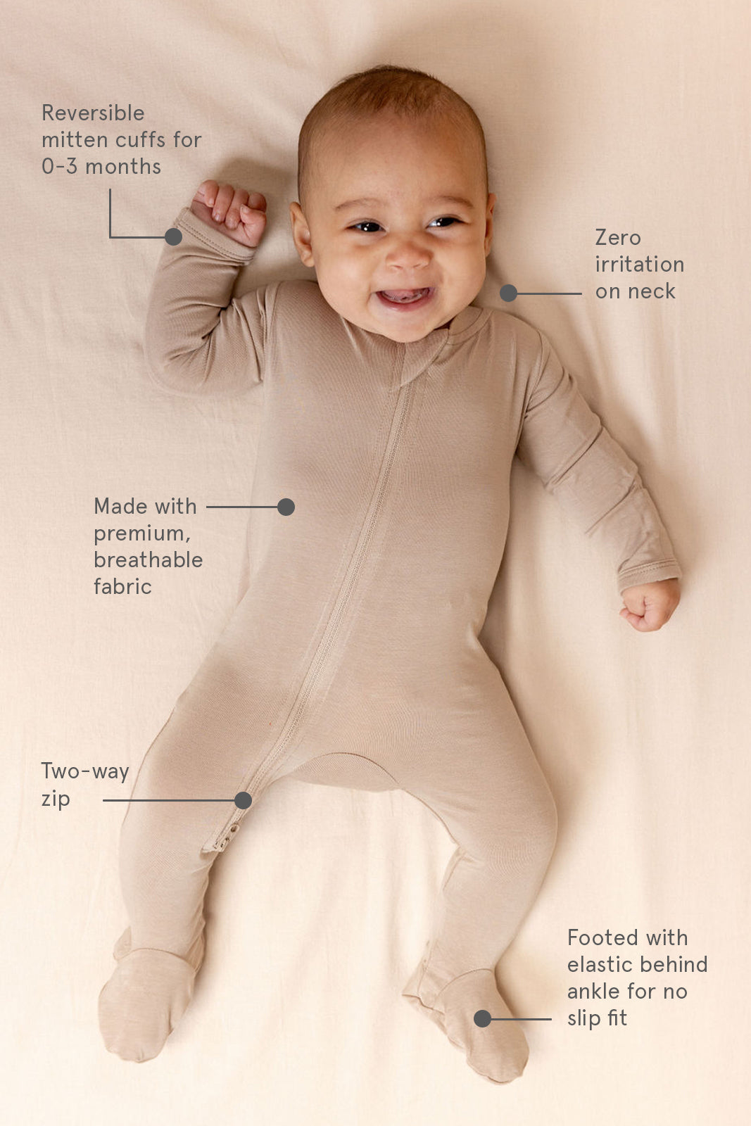 Baby wearing a beige onesie with text highlighting features, lying on a white surface.