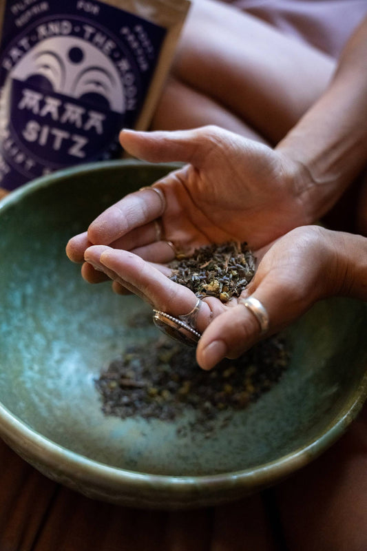 a person picking up a handful of mama sitz from a ceramic bowl