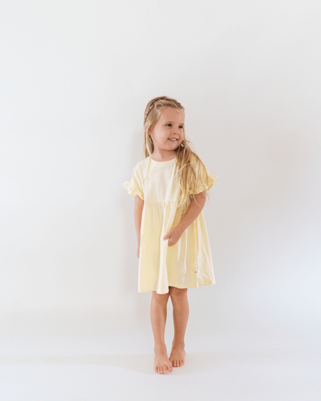 Young girl wearing a yellow dress against a white background