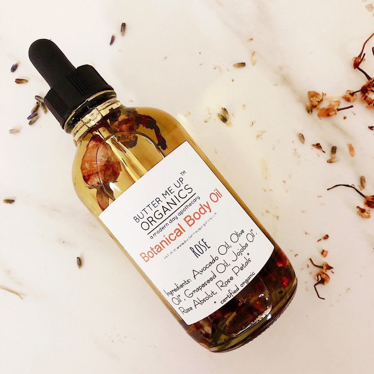 Butter Me Up Organics botanical body oil bottle with dropper on a light background