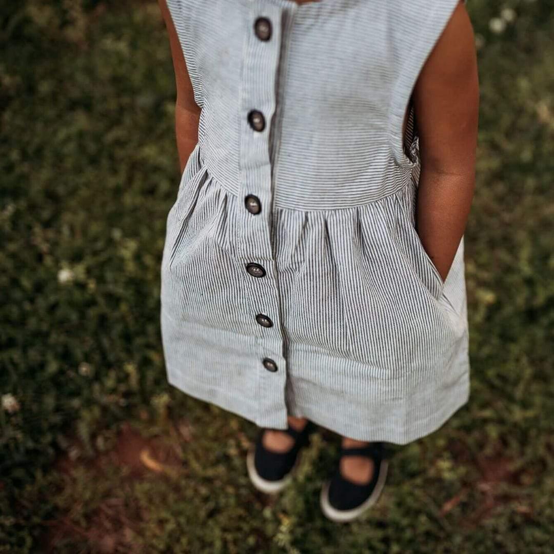 Person wearing a sleeveless button-up dress standing on grass