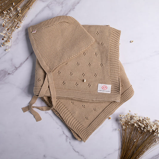 Beige knitted blanket with star patterns on a marble surface