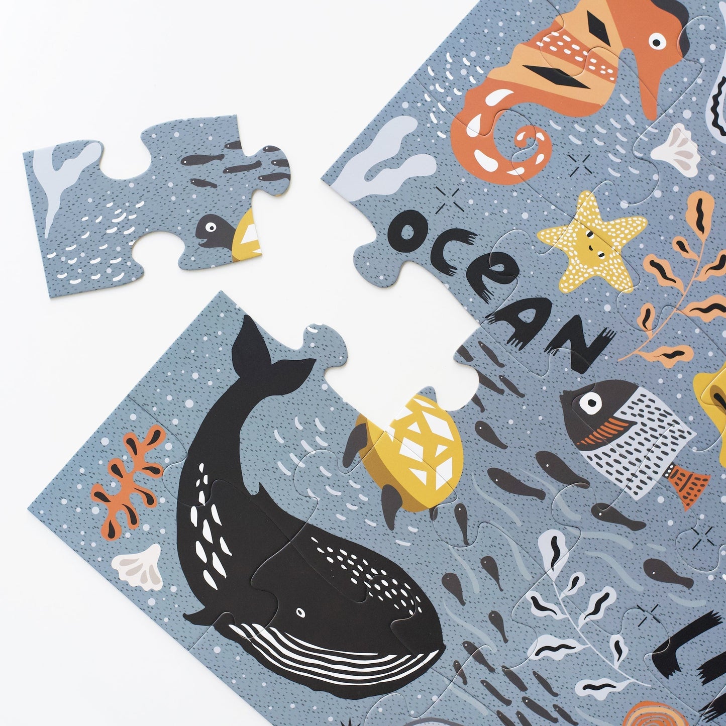 Children's puzzle with ocean-themed pieces featuring a whale, fish, and seahorse on a blue background.
