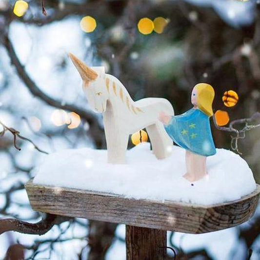 Snowy winter scene with wooden unicorn and fairy