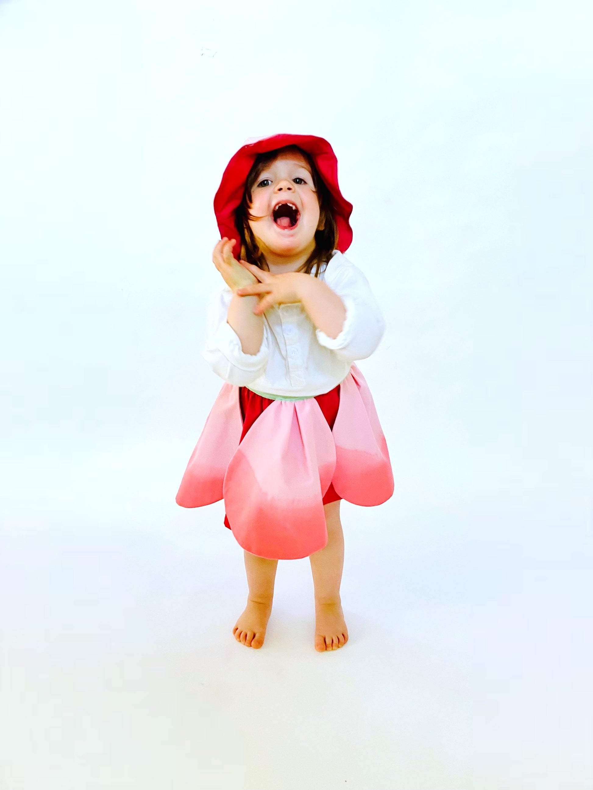 Child wearing a red dress and hat on a white background