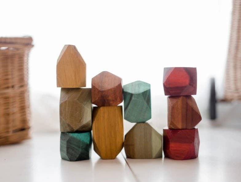 Colorful wooden gems stacked on a light surface with a wicker basket in the background.