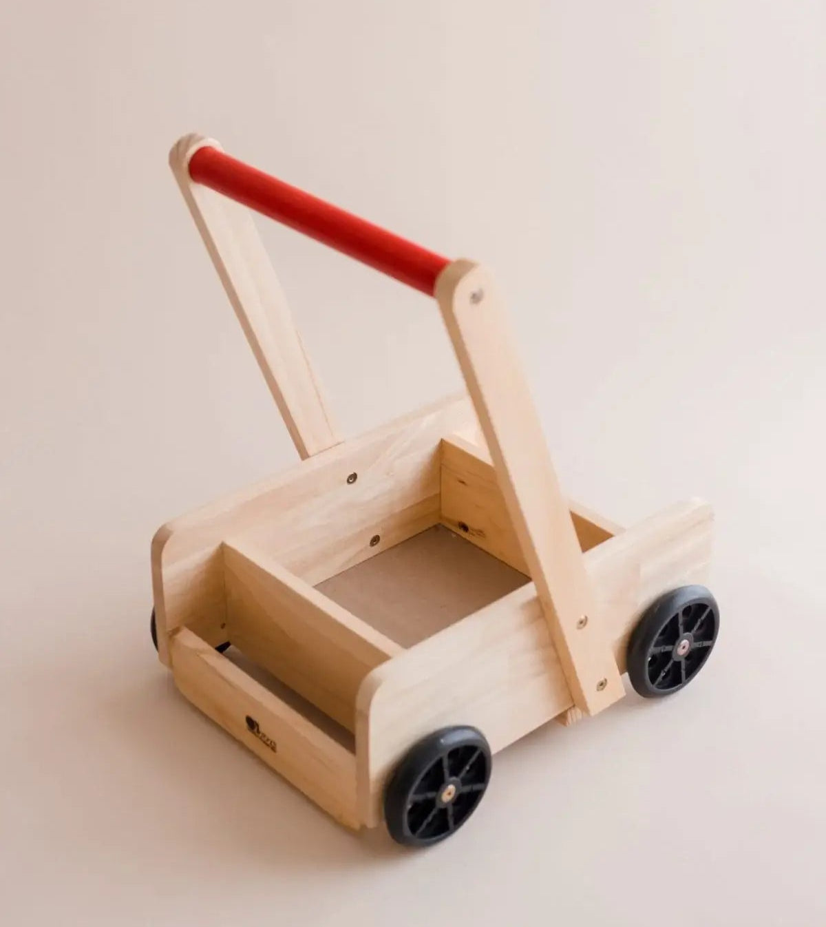 Wooden baby walker with a red handle on a beige background