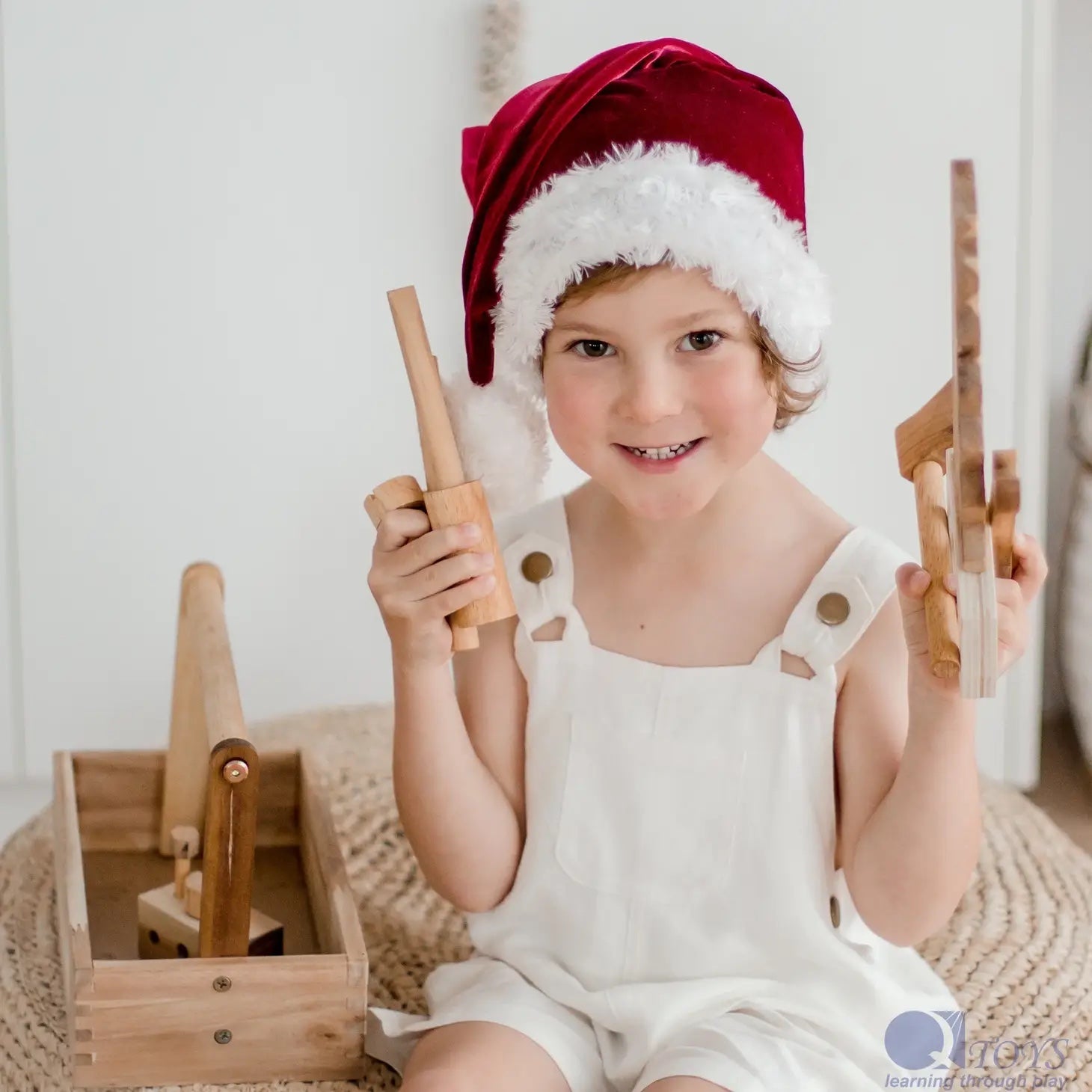 child wearing a Santa hat playing with wooden tool set