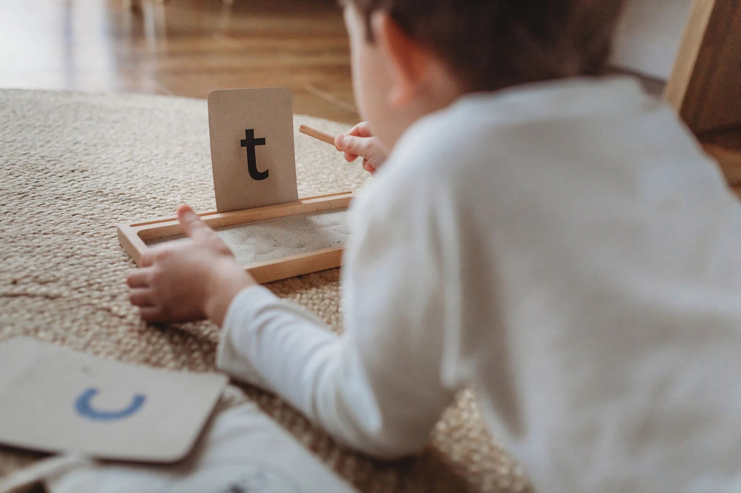 Kids practicing writing on a Sand Writing Tray
