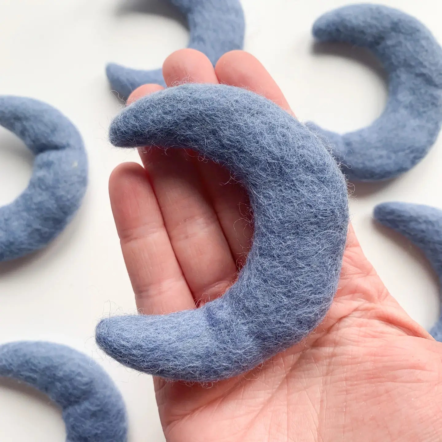 hand holding a blue felt moon
