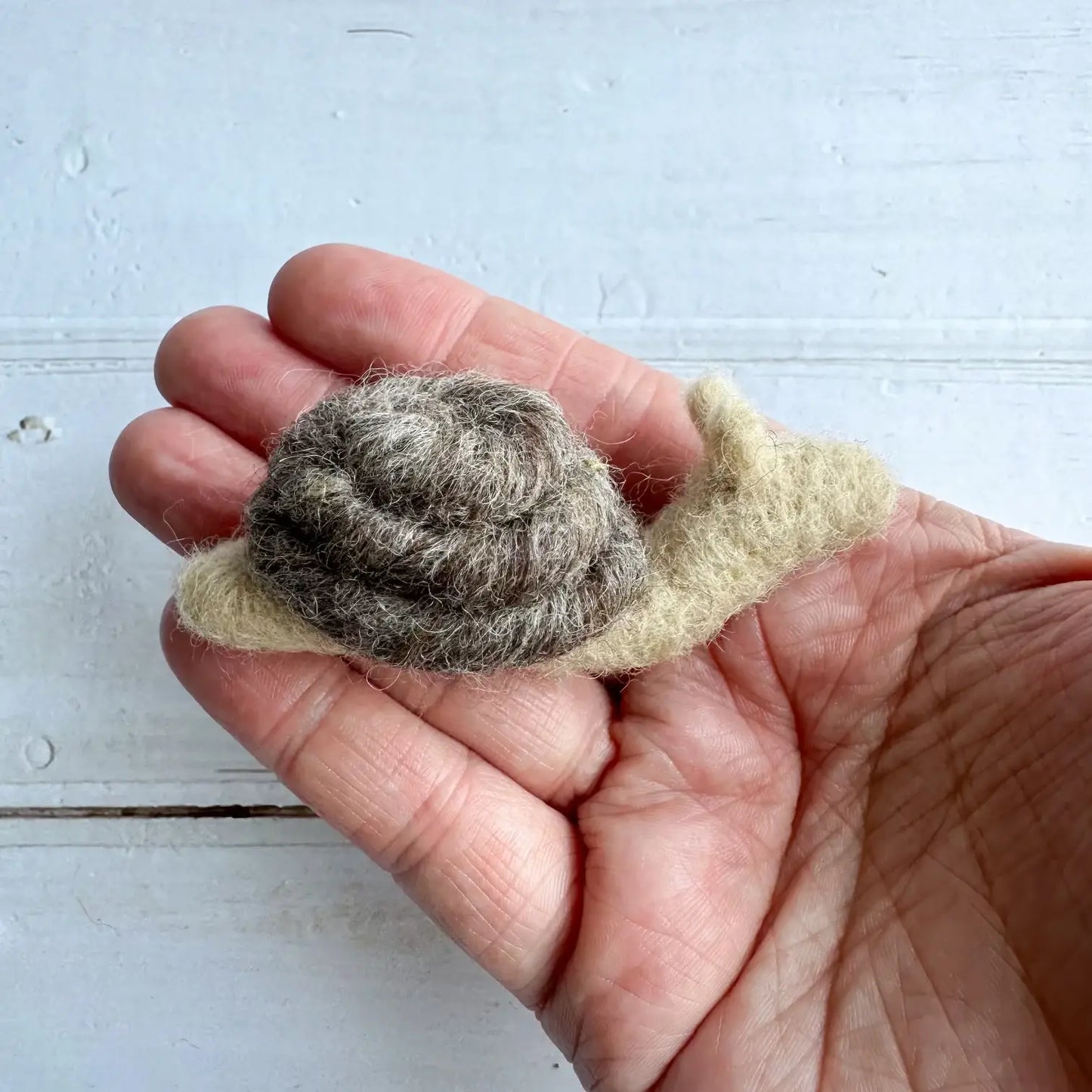 hand holding a grey felt snail