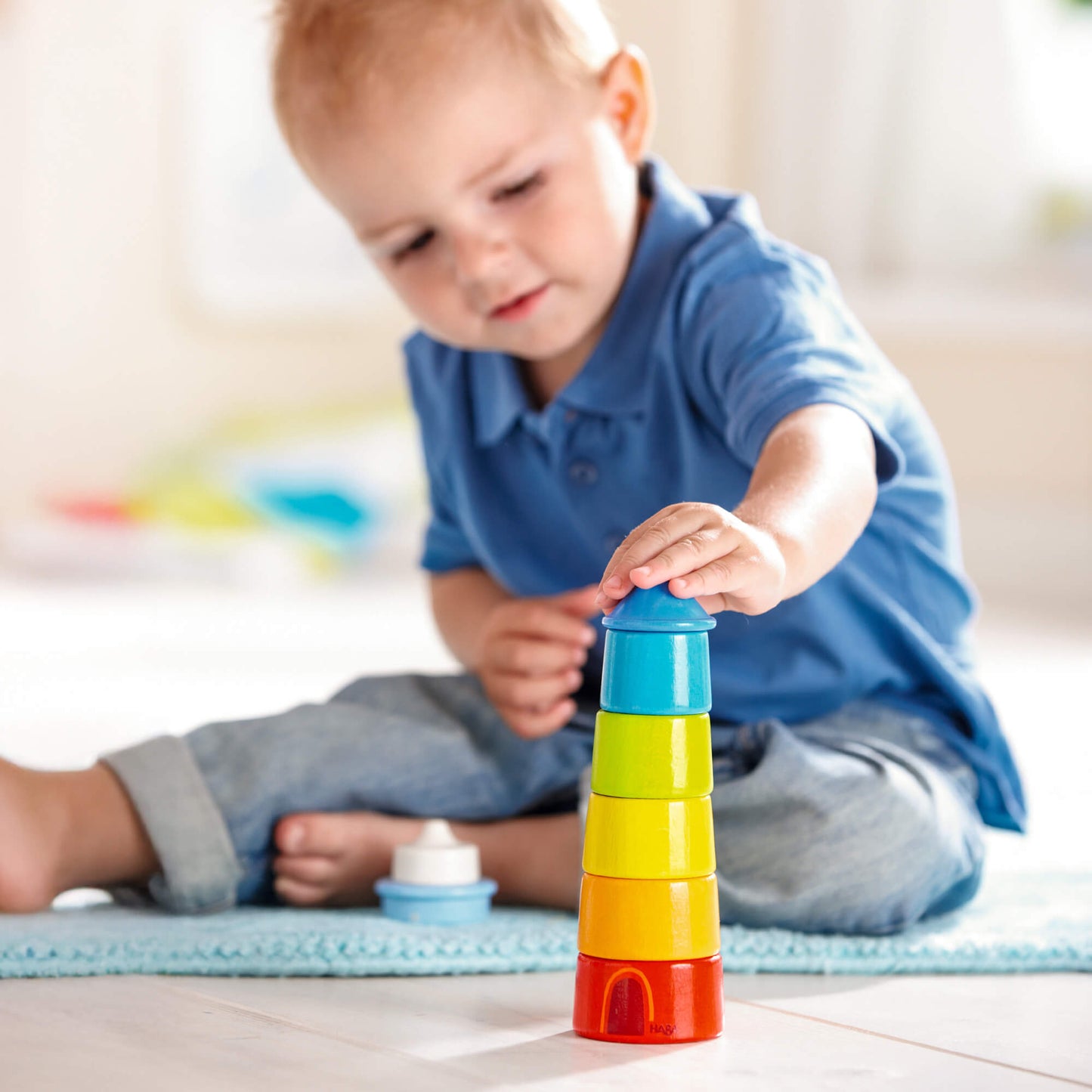 Child playing with colorful stacking blocks on a light surface.