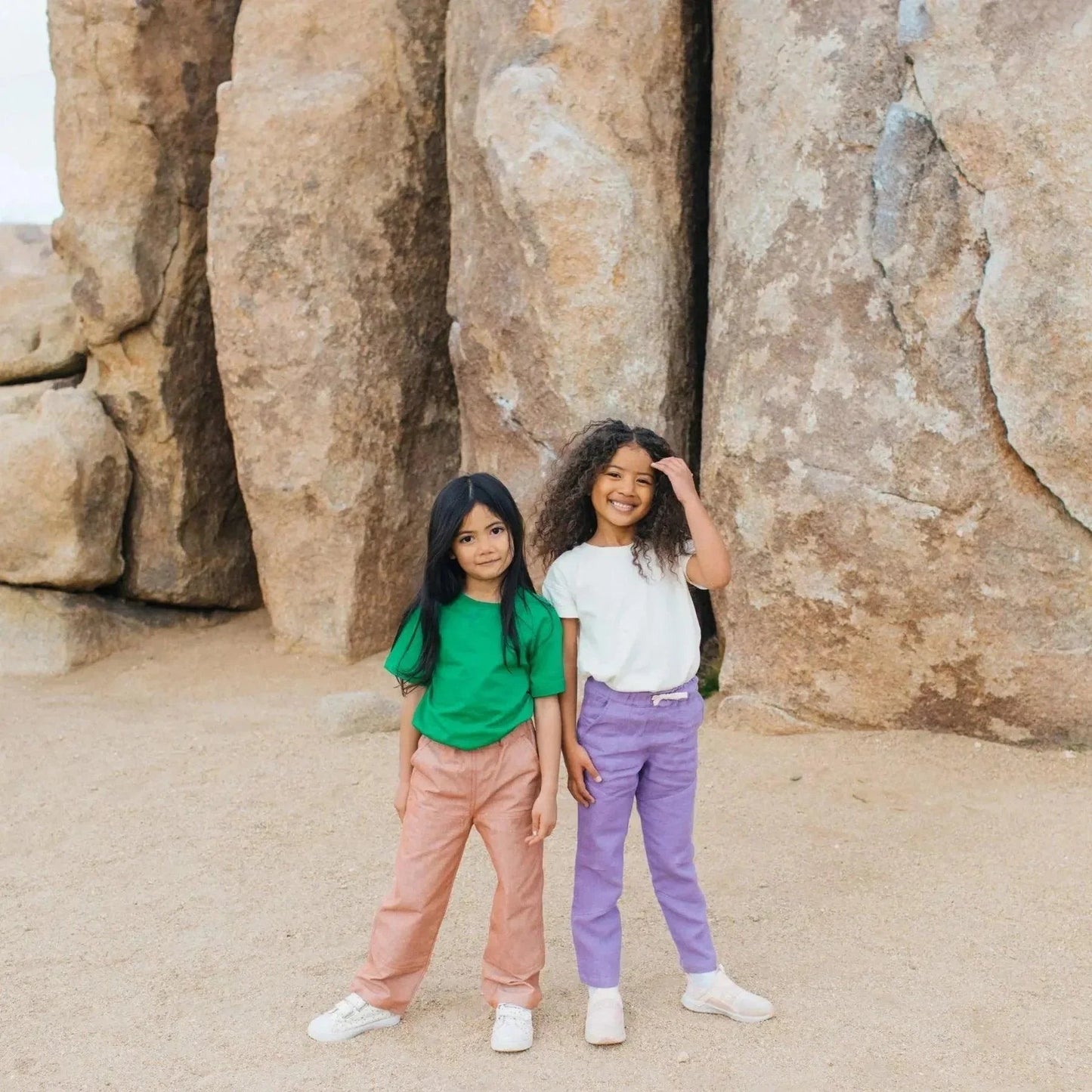 Two children standing in front of large rock formations.