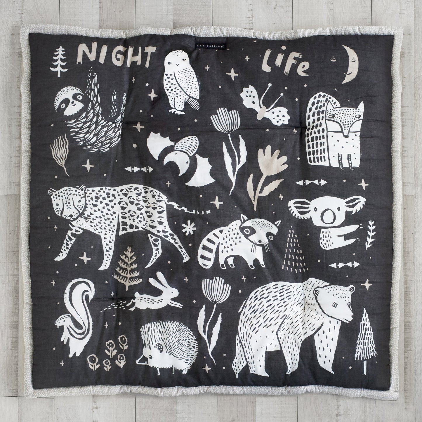 Black blanket with white animal illustrations and text on a wooden surface