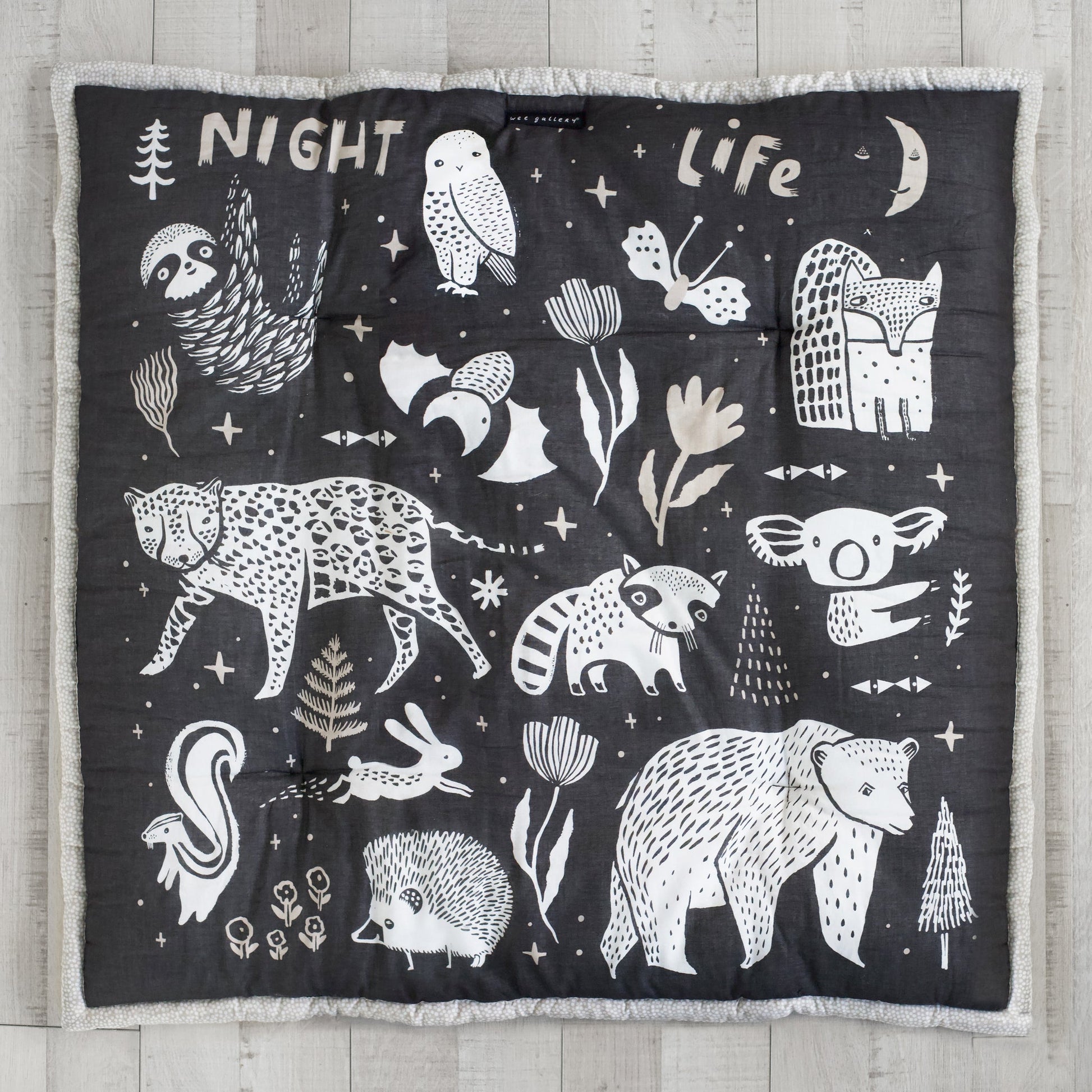Black blanket with white animal illustrations and text on a wooden surface